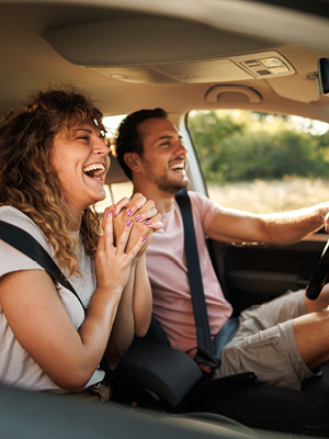 A man and woman driving in a car laughing
