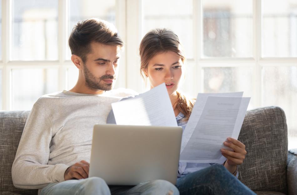 couple on a couch looking at papers and a laptop