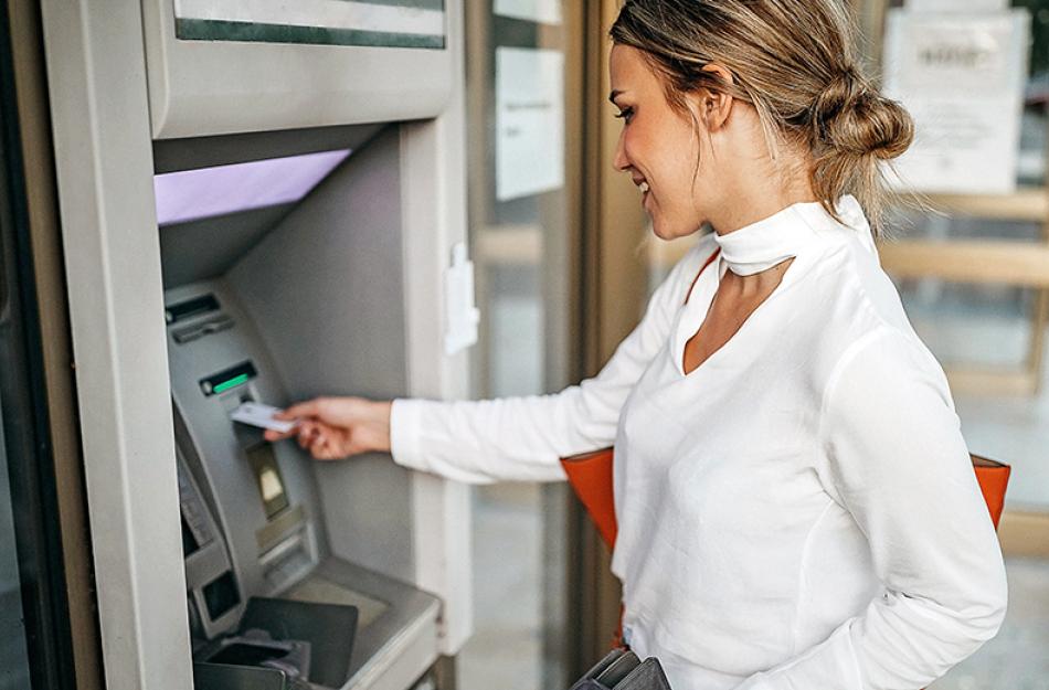 Person putting their debit card into an ATM.