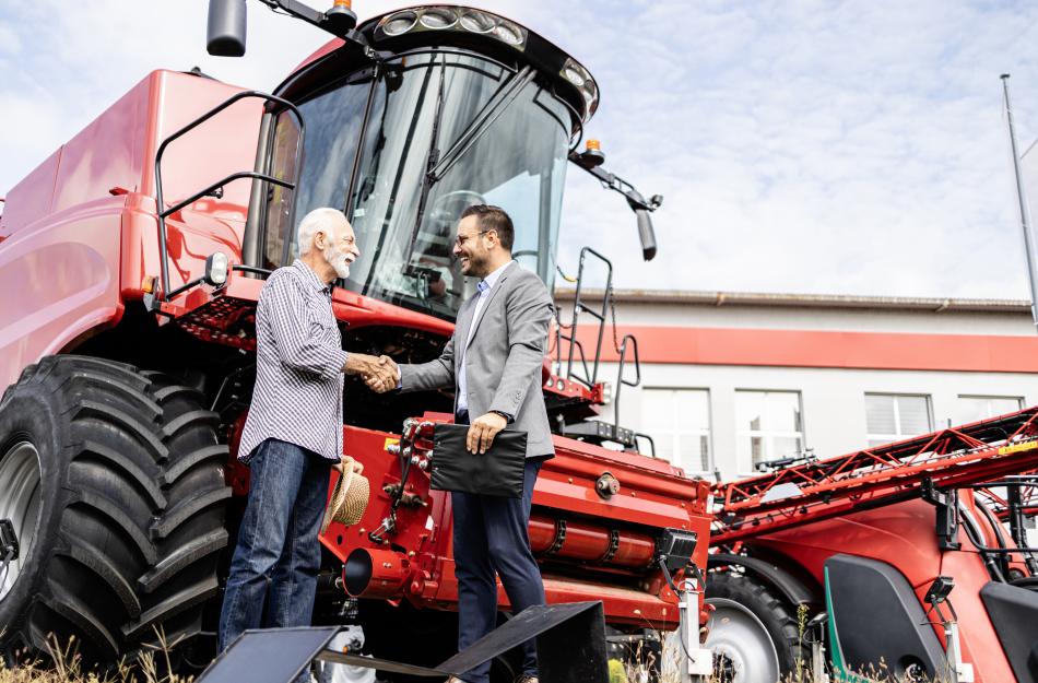 farmer talking to a banker in front of a combine