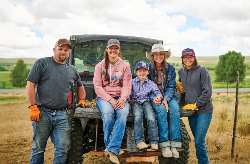 A family sitting on their utility vehicle on their farm.