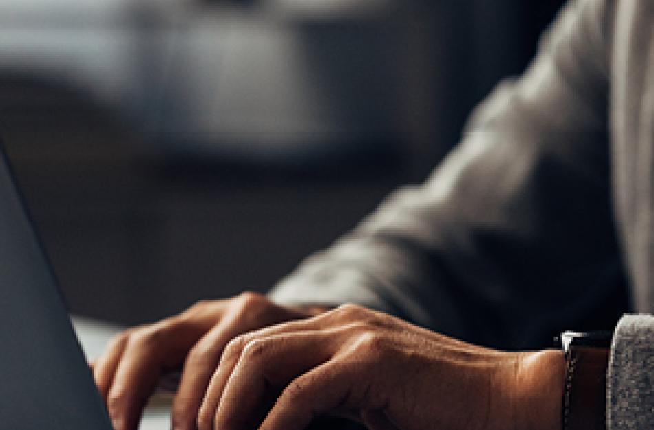Hands typing on a laptop