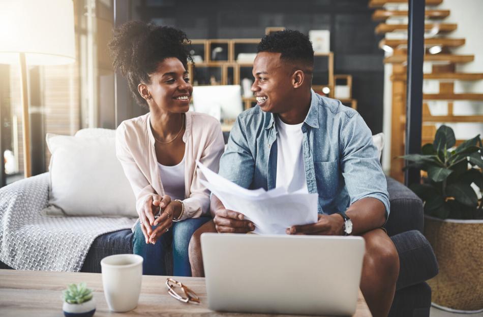 couple on a couch looking at papers and a laptop