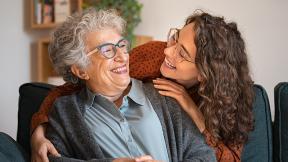 A person smiling and hugging her grandmother. 