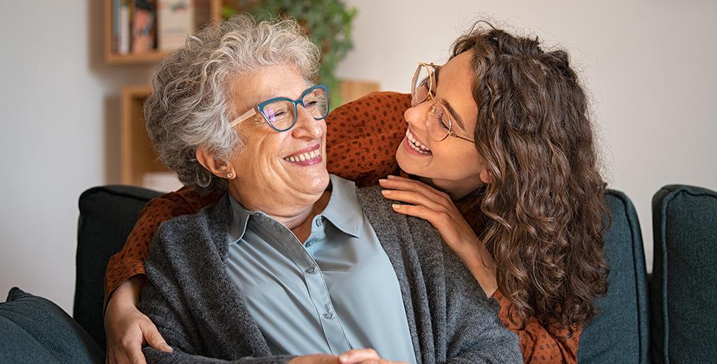 A person smiling and hugging her grandmother. 