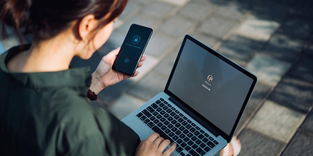 woman holding a phone while working at her laptop